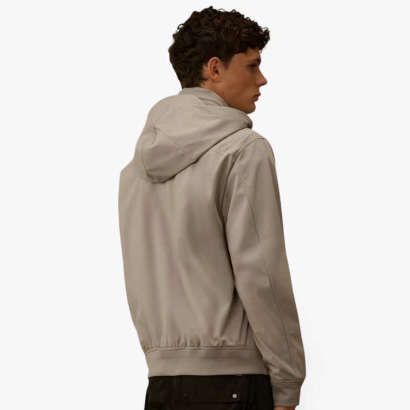 Veste technique CP COMPANY par RÆW DISTRICT, tissu imperméable avec capuche, détails modernes et logo visible.