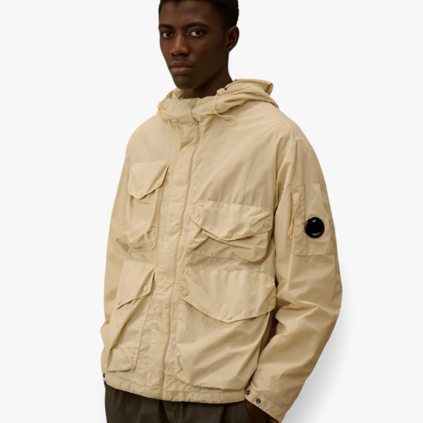 Veste Sahara de CP Company en tissu léger, couleur neutre, portée par un modèle, avec détails de design visibles.