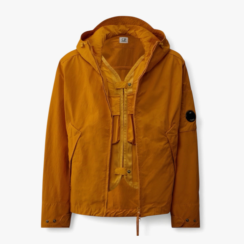 Veste orange de CP COMPANY en collaboration avec RÆW DISTRICT, vue de face avec détails de la texture et du design.